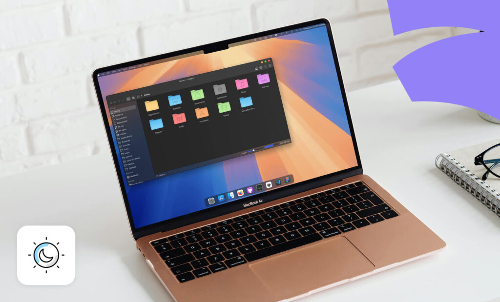 Laptop on a white desk showing a dark mode file manager on screen