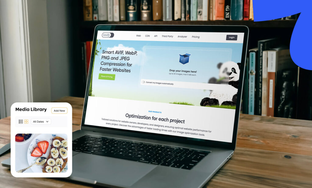 A laptop on a wooden table displaying the TinyPNG image compression website